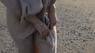 Güzel bayan, kameraya poz veren açık bej bir elbise giyiyor.