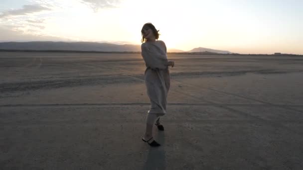 Pani w długiej beżowej sukience bielizny biegnie pozowanie o zachodzie słońca — Wideo stockowe