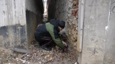 Sakallı endişeli bağımlı, kırık duvarda uyuşturucu arıyor.