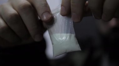 Kişi küçük plastik fermuarı beyaz tozla tutar