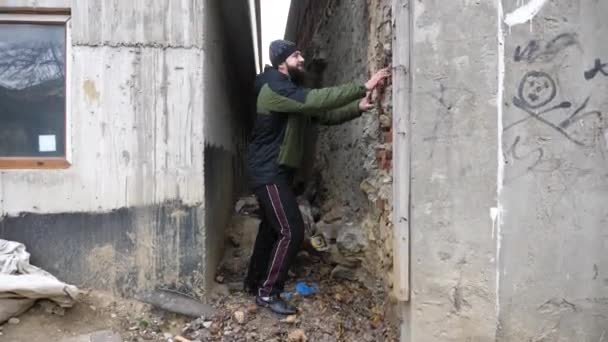 Hombre preocupado con barba busca droga en casa vieja grieta de la pared — Vídeos de Stock
