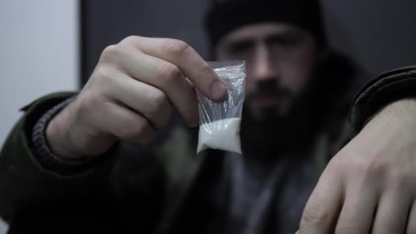 Занепокоєний хлопець дивиться на маленький застібку-блискавку з білим наркотичним порошком — стокове відео