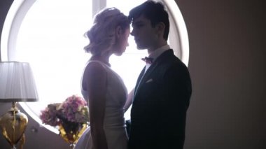 Güzel gelin ve damat, yuvarlak pencerenin yanında durur.