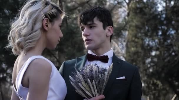 Chlap se dívá na ženu v bílých svatebních šatech s malou kyticí — Stock video
