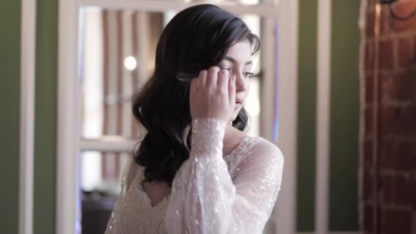 Jeune mariée en robe élégante redresse les cheveux au miroir — Video