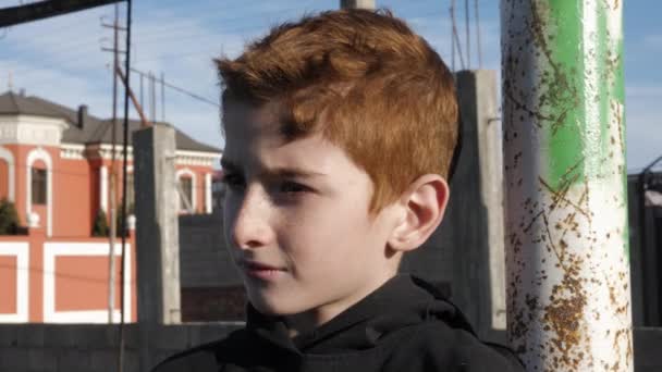 Upprörd liten pojke lutar sig mot gammal metall stång på fotbollsplan — Stockvideo