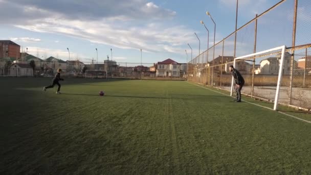 Schooljongen stuurt bal langs vader keeper op erf veld — Stockvideo