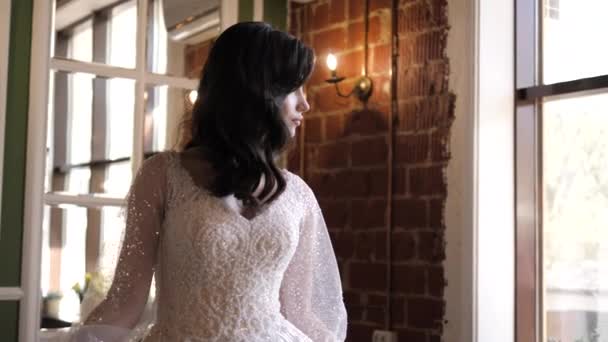 Drömmande dam i bröllopsklänning ser ut genom fönstret i studio Stockfilm