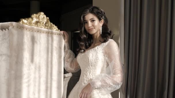 Braut in stylischem Kleid lehnt im Atelier auf Vintage-Thron — Stockvideo