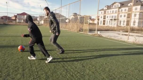 Hijo con padre juega al fútbol en el campo verde por la noche — Vídeo de stock