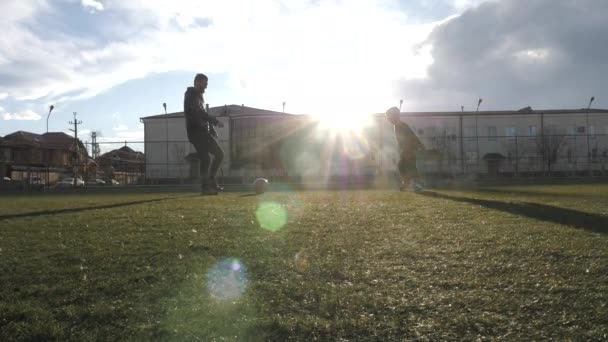 Silhuetter av son och far spelar fotboll på planen Stockfilm