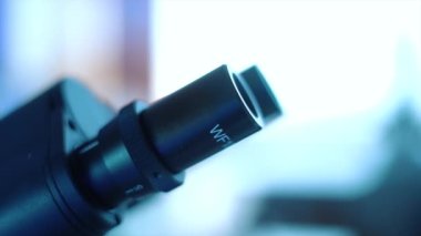 Laboratuvarda mikroskopla araştıran kadın tıp doktoru ya da araştırmacı bilim adamı. Biyolojik kimya örneklerini araştırmak için kimyasal sıvı içeren laboratuvar bardakları.