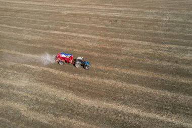 Traktör alana yapay gübre yayıyor.