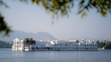 Pichola Gölü, Udaipur, Rajasthan, Hindistan 'da güneşli bir kış gününde insansız küçük bir adada lüks bir otel.