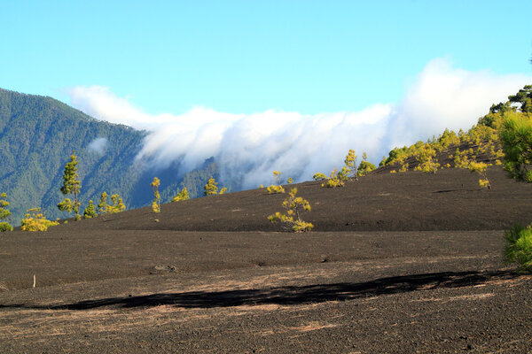 Creeping clouds against volcano wall