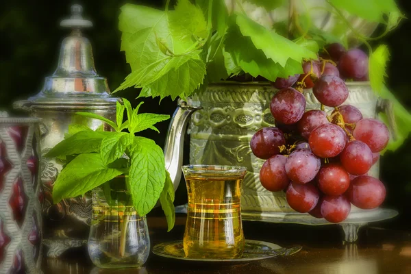 Té de menta y uvas rojas en la mesa árabe —  Fotos de Stock