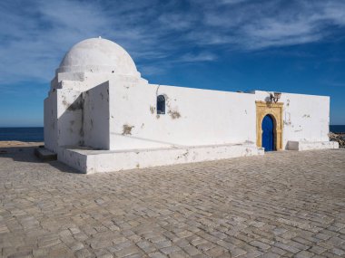 Sidi Ghadamisi mozolesi, Manastır 'ın güneşli doğusunda gururla duruyor. Beyaz mimarisi, Tunus 'ta mükemmel bir kış öğleden sonrası boyunca derin mavi gökyüzü ve ışıl ışıl Akdeniz ile güzel bir tezat oluşturuyor..