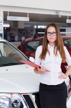 kırmızı bir klasörle showroom duran genç kadın