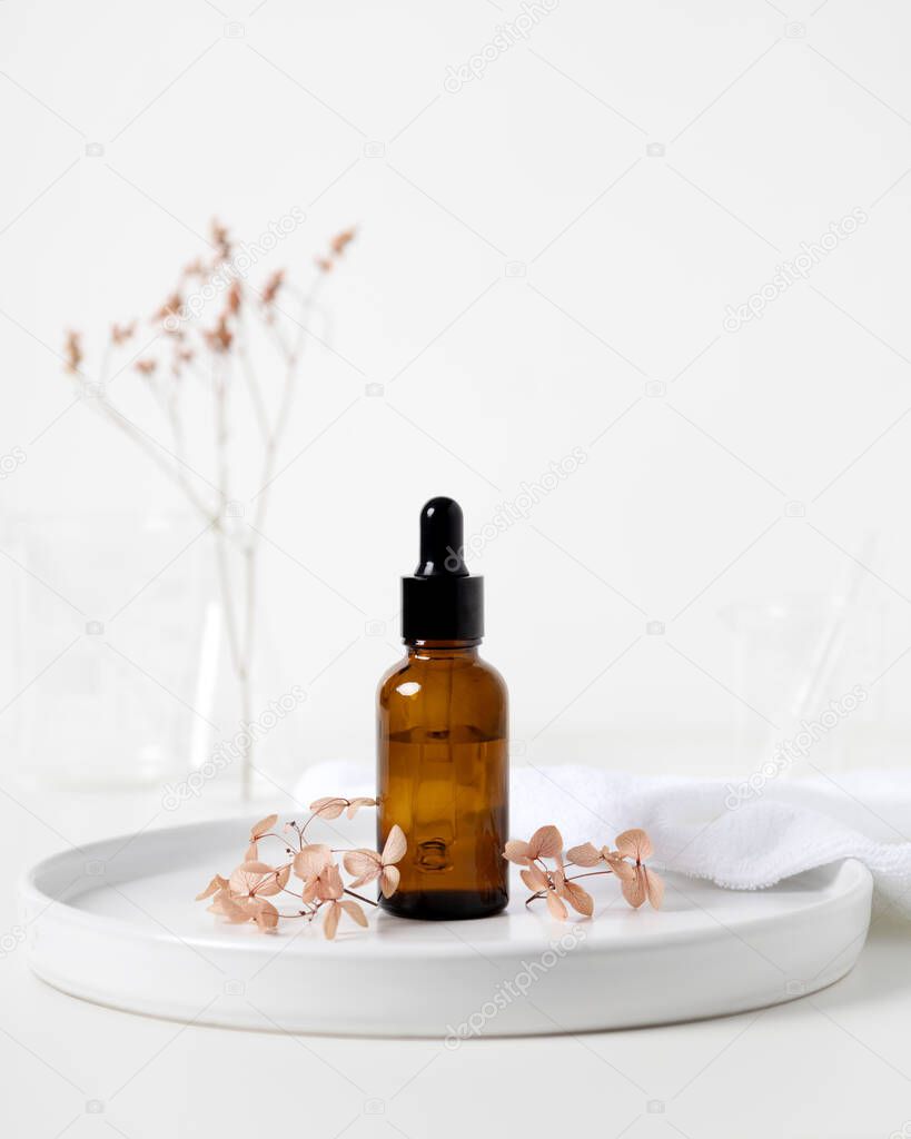 Brown serum dropper bottle with relaxing aroma flower and laboratory flask photography