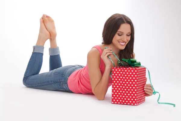 Beautiful woman in a red t-shirt and blue jeans enjoys gift on Valentines day — Stock Photo, Image
