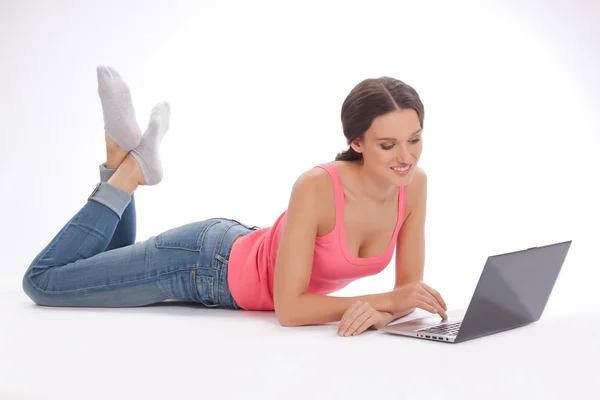 Schöne junge Frau in roter Weste und blauer Jeans mit Laptop — Stockfoto