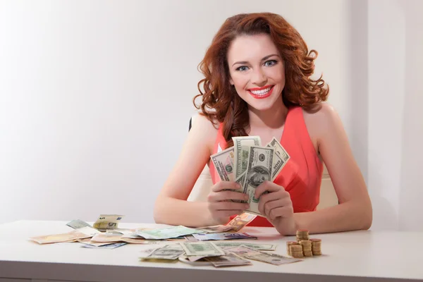 Beautiful business woman in pink dress sdet at  table on which  money — Stock Photo, Image