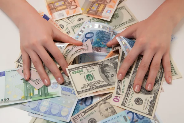 Женщины могут наслаждаться деньгами в евро и долларах, лежащих на столе Лицензионные Стоковые Фото