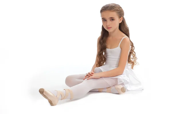 Young girl in her dance clothes reaching down to touch her foot. — Stock Photo, Image