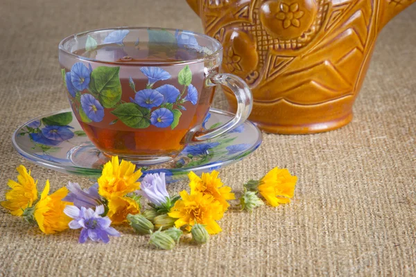 Glas Tee mit gelben und blauen Blüten — Stockfoto