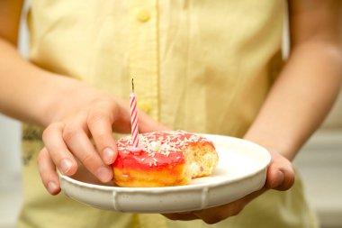 12 yaşındaki bir çocuğun elinde taze yenmiş bir donut var.