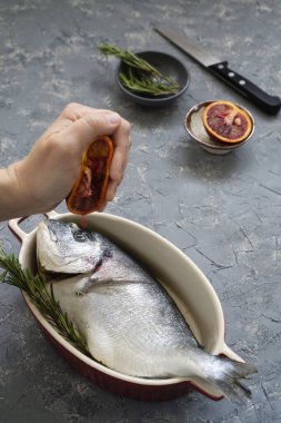 Turunçgil ve biberiyeli deniz ürünleri pişirmek. Taze balığı kızarmaya ya da kırmızı portakallarla kızartmaya hazırlama süreci.