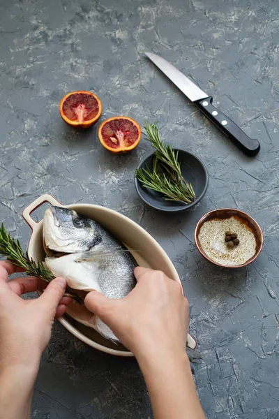 Cooking seafood with citrus and rosemary. The process of preparing fresh fish for roasting or frying with red oranges