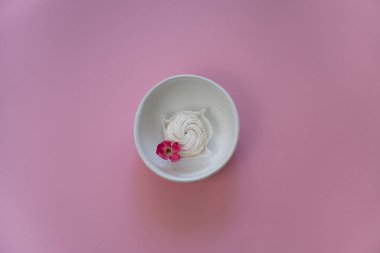 Yuvarlak beyaz bir tabakta tek şekerli pembe arka plan. Bahar, doğum günü ya da anneler gününde tebrik kartı..