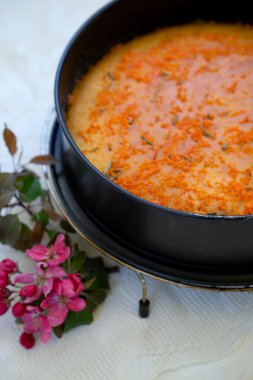 Kana bulanmış portakal kabuklu turta. Bahar çiçekleriyle birlikte masada. Kahvaltıda sıcak bir bahar günü için turta.