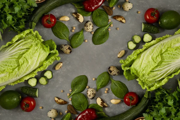 Diet plan with greens and fresh vegetables in a paper notebook on a gray table surface.