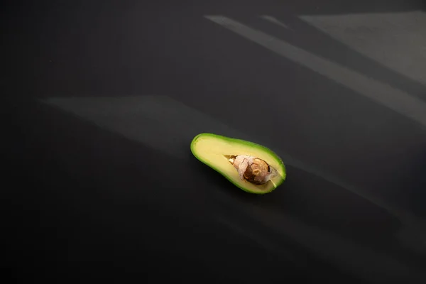 Eine Hälfte Reife Avocado Mit Knochen Auf Schwarzem Hintergrund Und — Stockfoto