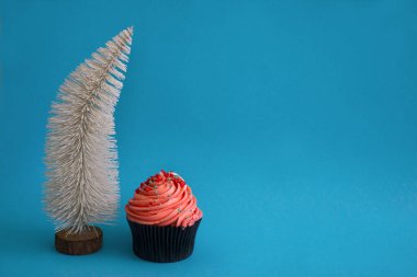 Noel beyaz Noel ağacı ve mavi arka planda pembe kremalı pasta. Yeni yıl partisi için bir kutlama ya da davet alanı kopyala