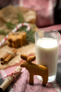 Yeni yıl atıştırmalıkları bademli tatlı pastalar ve renkli ışıklarla süslenmiş çizgili lolipoplu süt.