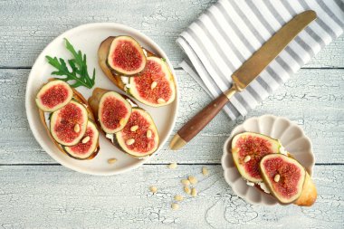 Yumuşak keçi peyniri üzerine taze incir, roka, kızarmış ekmek ve balla sağlıklı bir kahvaltı.