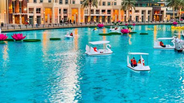 Dubai, Birleşik Arap Emirlikleri - 1 Ocak 2021: İnsanlar güzel Burj Halife Gölü 'nde DSF mevsiminde kuğu şekilli kürek tekneleriyle gezmekten keyif alıyorlar