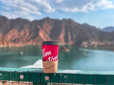 Dubai, Birleşik Arap Emirlikleri - 15 Mayıs 2021: Dağlarda kapağı olan kırmızı Tim Hortons kahve fincanı. Tim Hortons dünya çapında ünlü bir fast food ve kahve zinciri..
