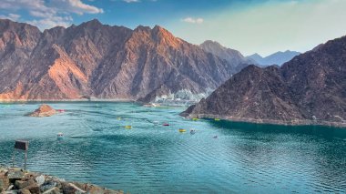 Hatta Dam Lake in mountains enclave region of Dubai, United Arab Emirates is famous tourist attraction with scenery and place to enjoy kayaking boat ride and other water adventure activities. clipart