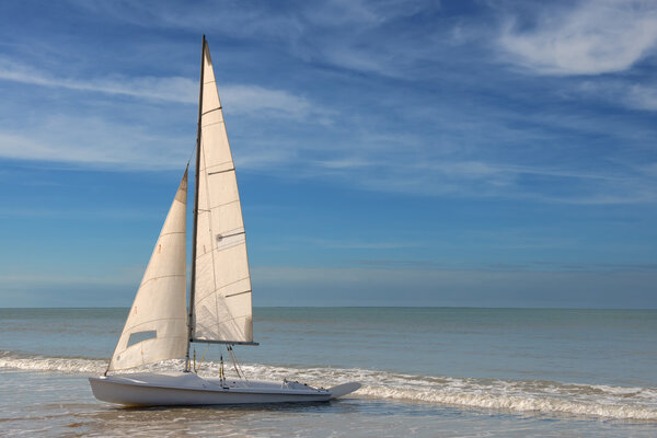 Little white sailboat grounded on a beach