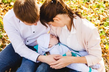 Anne ve babasının bebekleri var. Sonbaharda parkta ya da ormanda yürüyen küçük bir çocuk. Sarı yapraklar, doğanın güzelliği. Çocuk ve ebeveyn arasındaki iletişim.