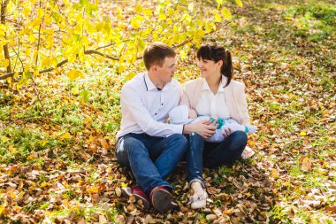 Anne ve babasının bebekleri var. Sonbaharda parkta ya da ormanda yürüyen küçük bir çocuk. Sarı yapraklar, doğanın güzelliği. Çocuk ve ebeveyn arasındaki iletişim.