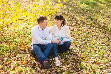 Anne ve babasının bebekleri var. Sonbaharda parkta ya da ormanda yürüyen küçük bir çocuk. Sarı yapraklar, doğanın güzelliği. Çocuk ve ebeveyn arasındaki iletişim.