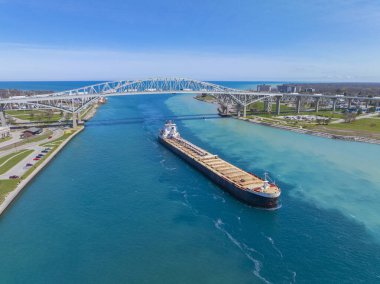 Toplu taşıyıcı St. Clair Nehri hava sahasında yelken açtı. Bu nehir Port Huron, Michigan, ABD (sağda) ve Point Edward, Ontario, Kanada 'yı bölmüştür (solda).).