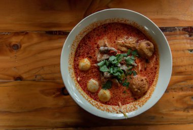 Baharatlı Tom yum domuz çorbası ya da baharatlı limon otu aromalı çorba ve ahşap masada seramik kasede balık köftesi. Üst görünüm, kopyala boşluk, özellikle odak yok,.