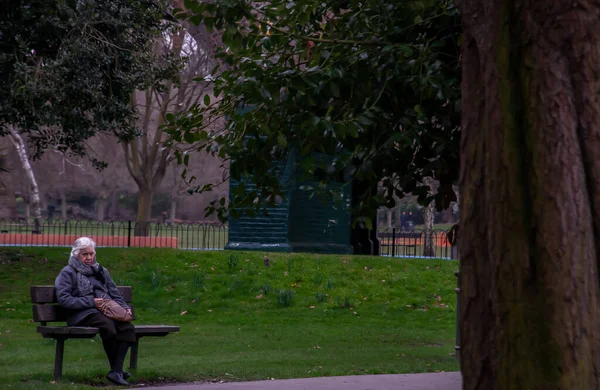 ロンドン イギリス 2019年4月12日 公園のベンチで木製の椅子に座っている高齢者の白人女性 特に焦点がない — ストック写真