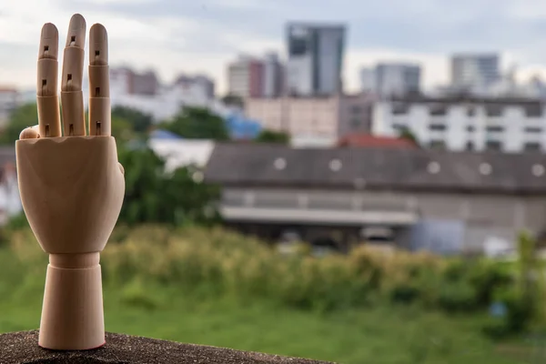 Wooden Hand Puppet showing three fingers hand on a city background. Symbolic support for democracy, Copy space.